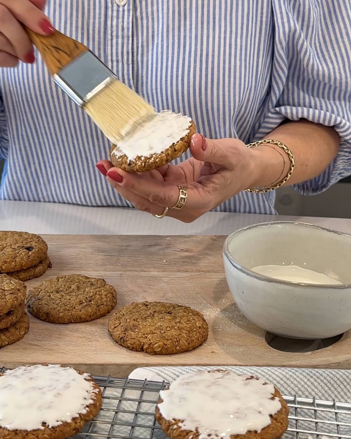 brushing royal icing onto baked iced oatmeal cookies