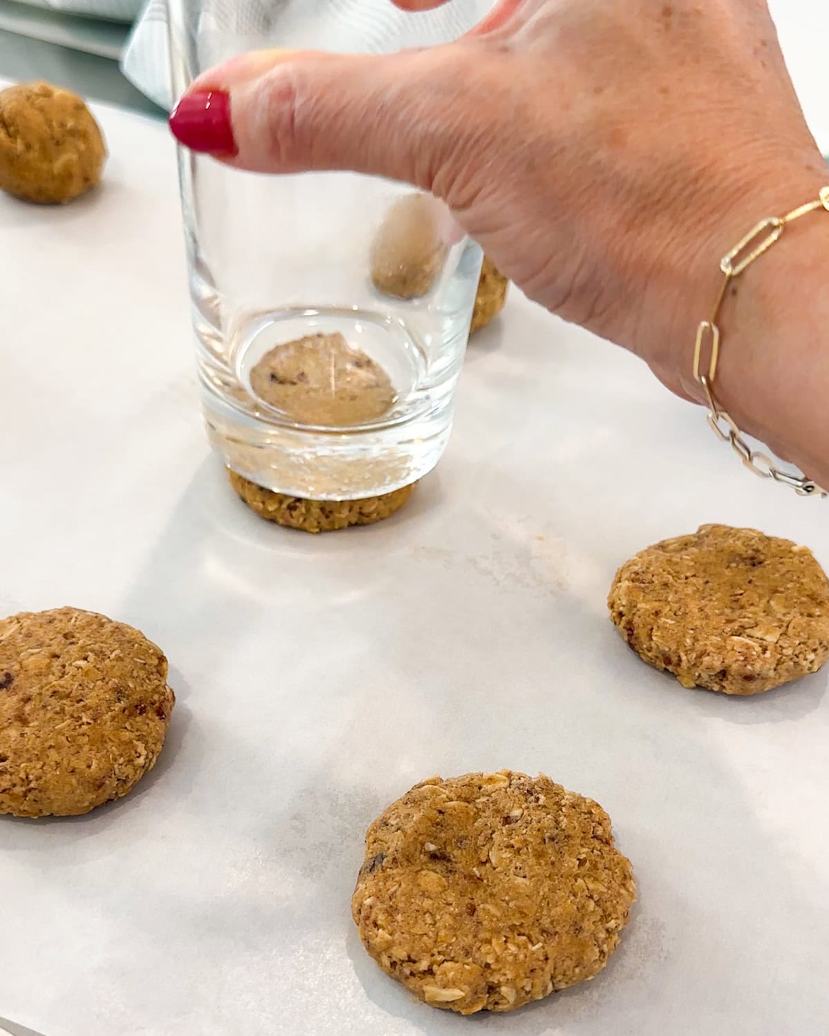 flattening oatmeal cookie dough balls with the bottom of a glass before baking.