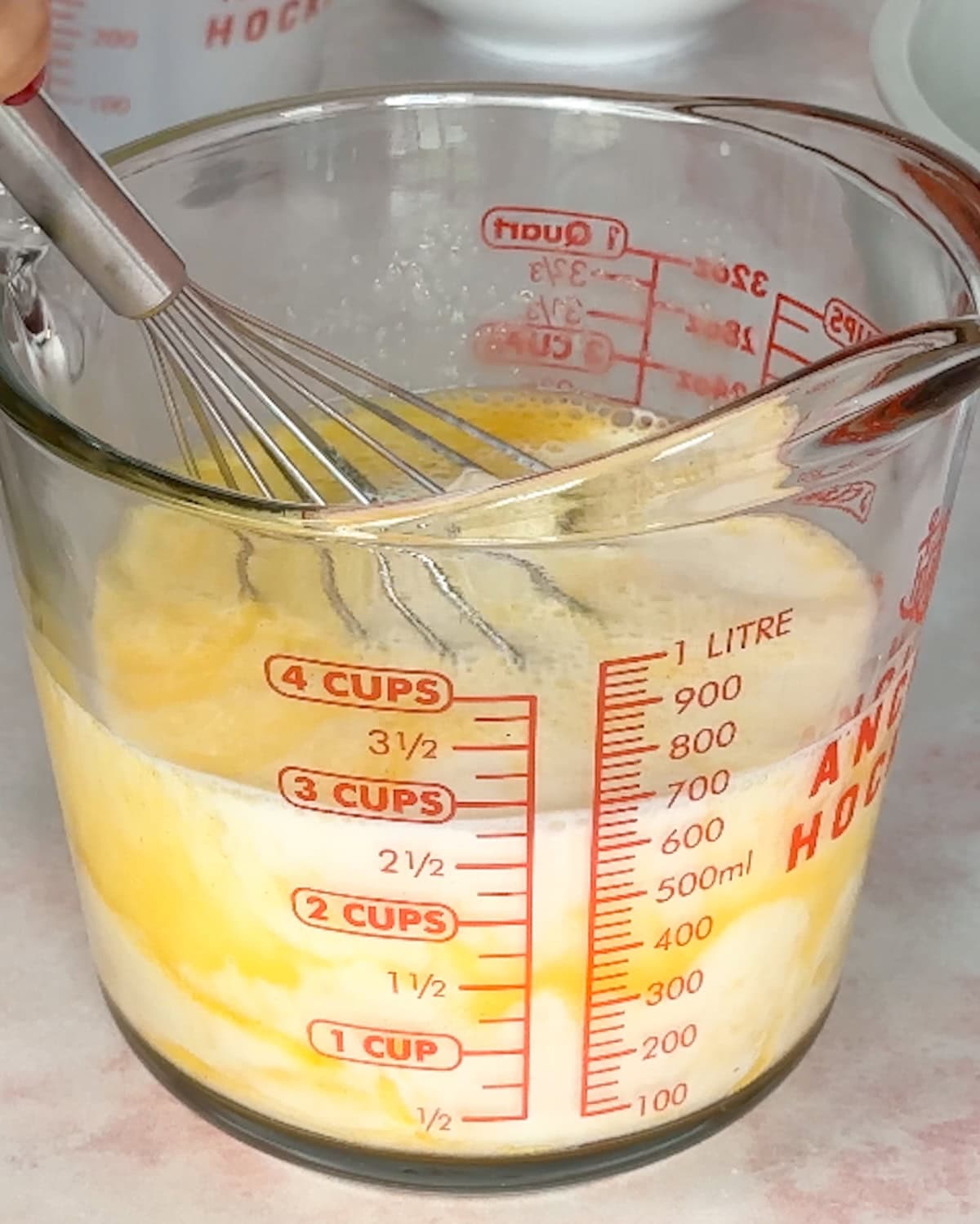 eggs and milk whisked together in a measuring cup for bread pudding