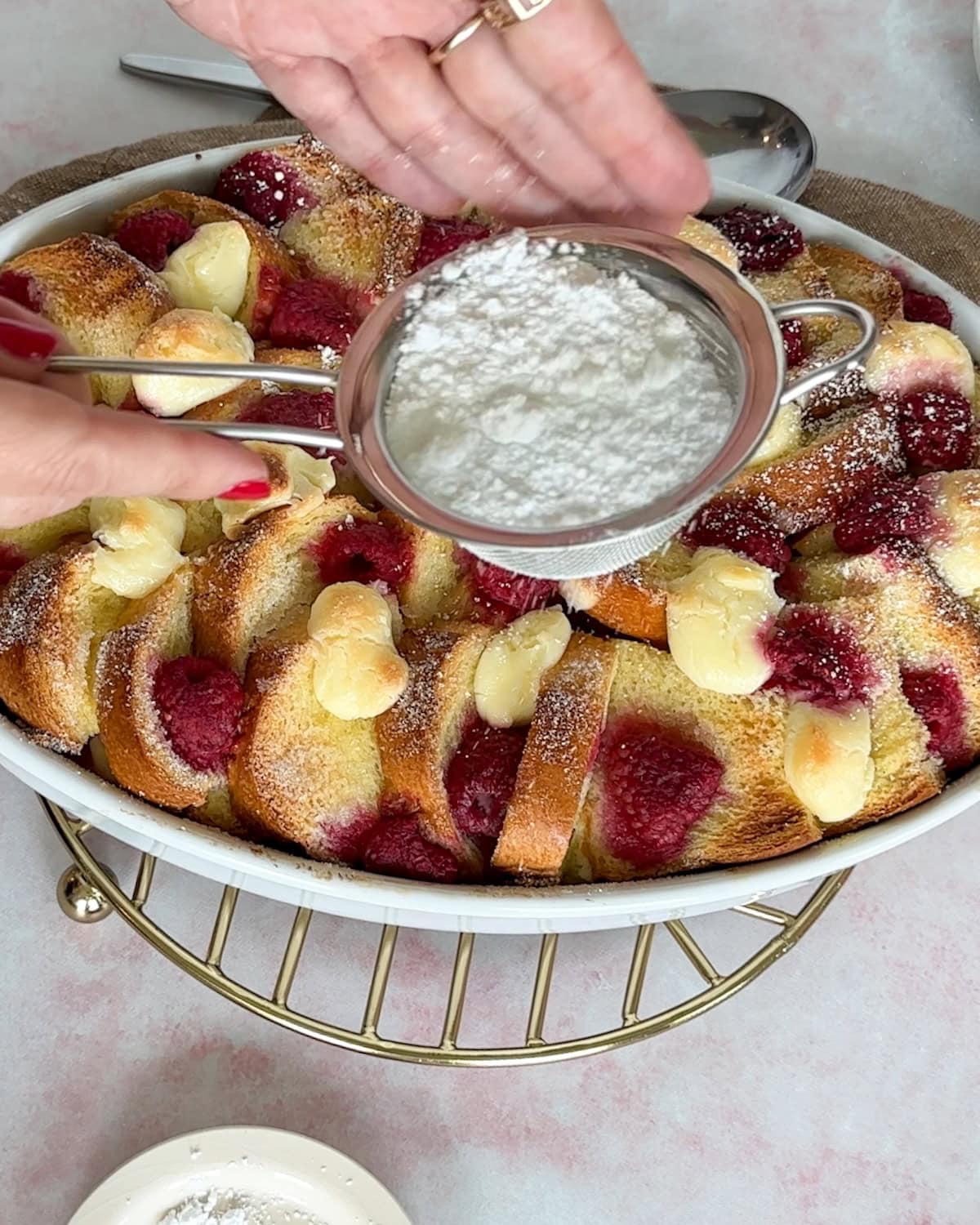 dusting top of raspberry bread pudding french toast bake with confectioners' sugar after baking.