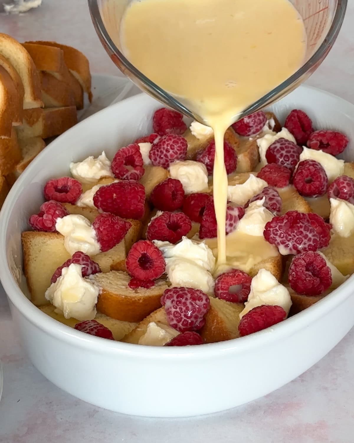 pouring custard on first layer of french toast bake.