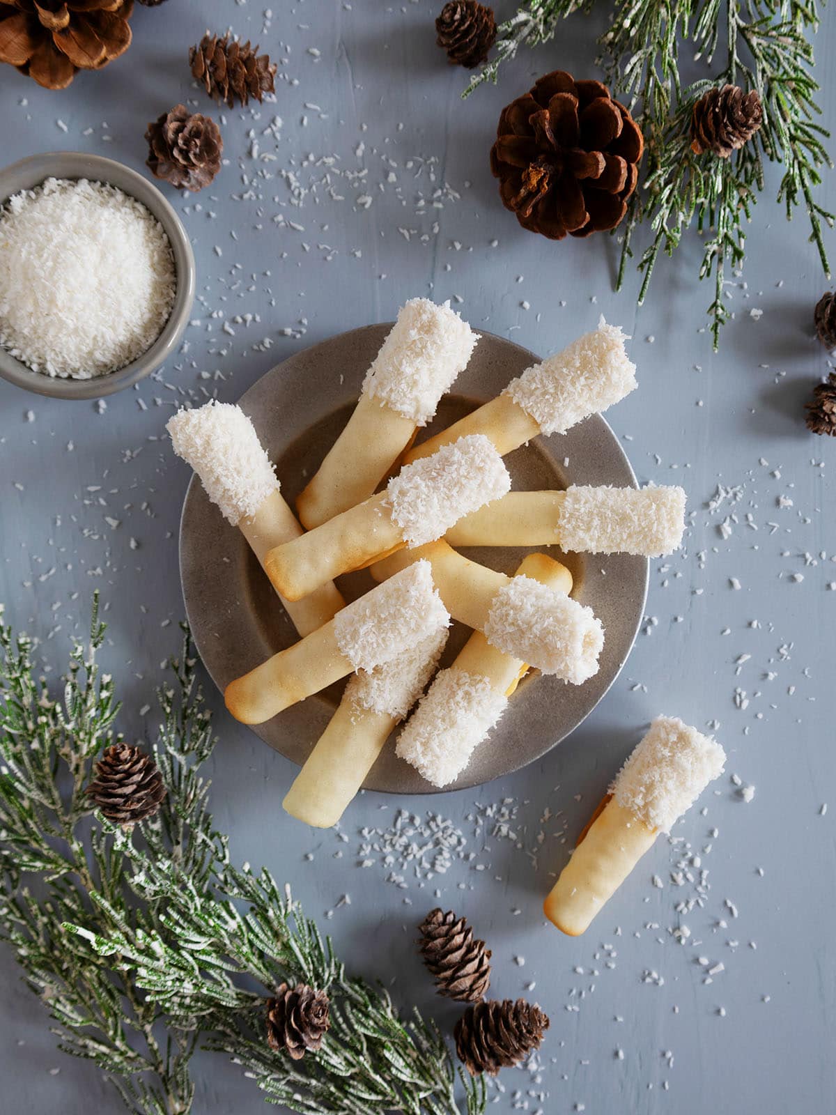 Top view of a plate of coconut pirouette cookies next to holiday decorations.