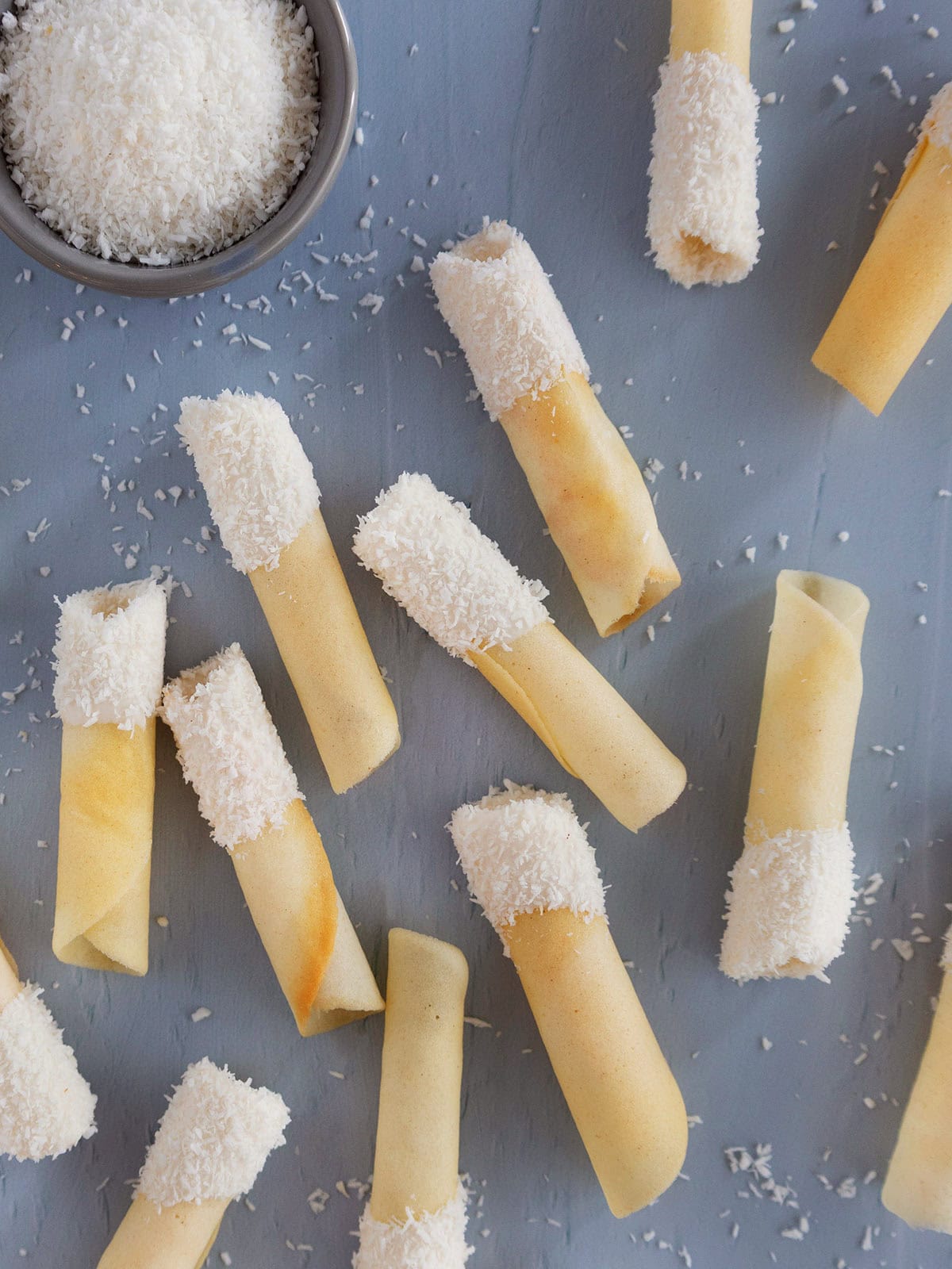 Coconut pirouettes spread out on a blue countertop.