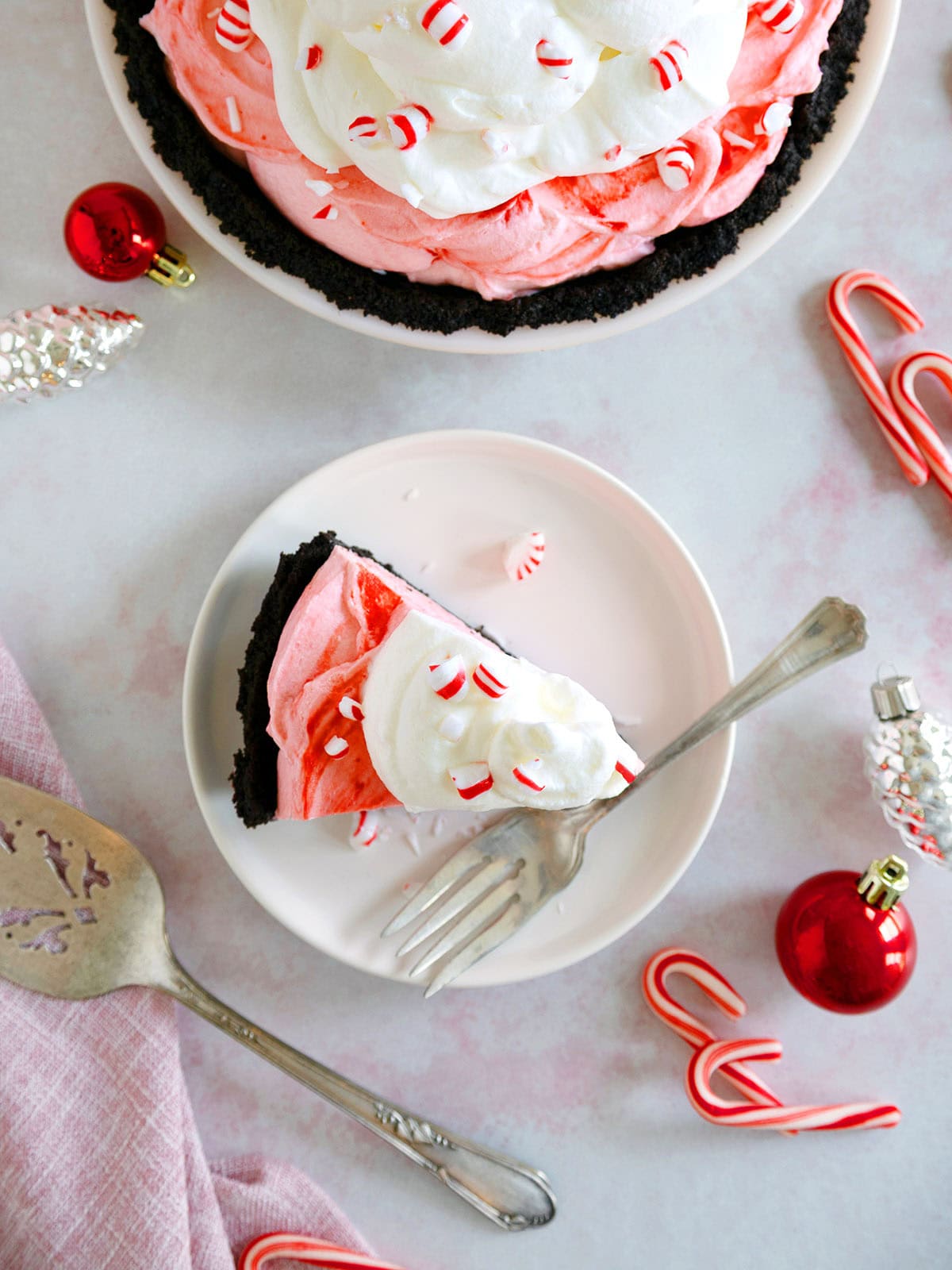 The top of a slice of peppermint pie on a dessert plate next to the rest of the pie.