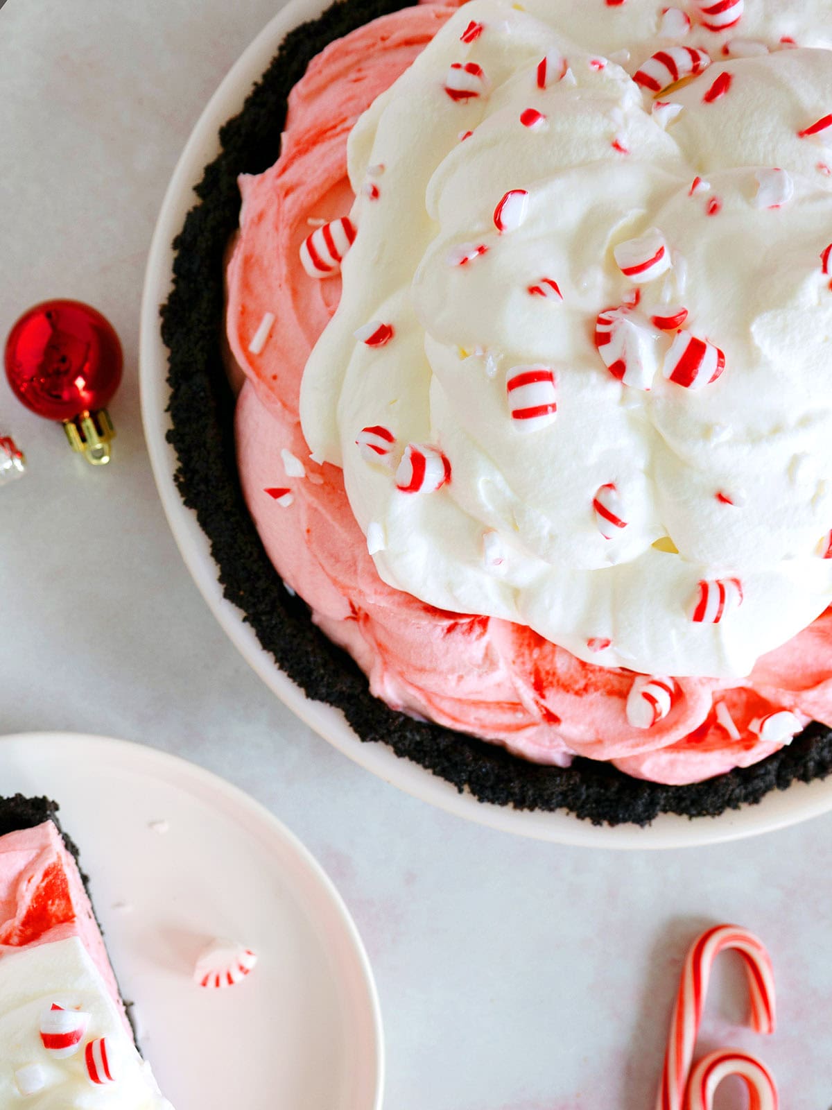 Top of a peppermint pie next to candy canes and a small dessert plate.
