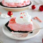 A slice of peppermint pie on a small dessert plate next to a fork.