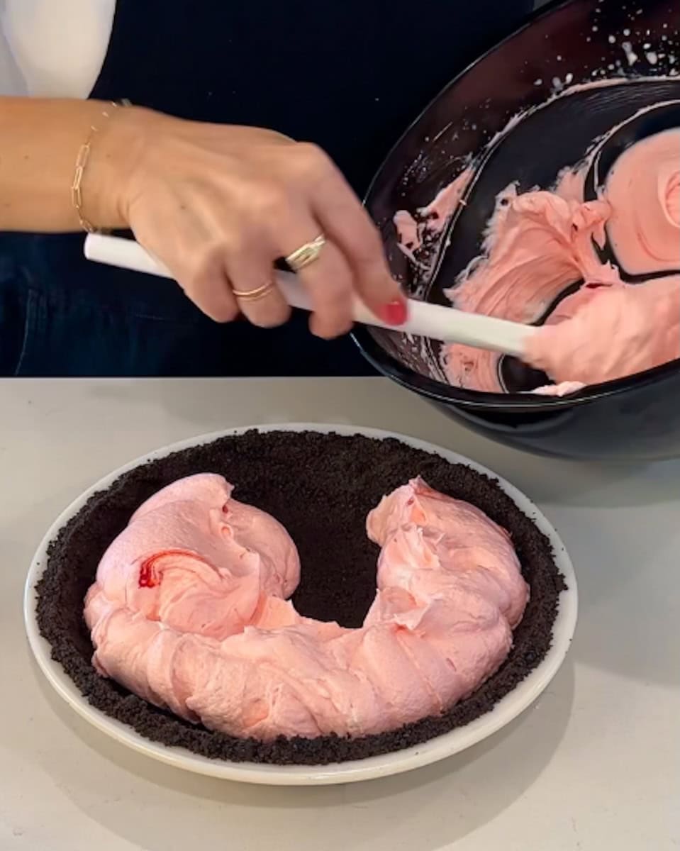 Spooning peppermint pie filling into the crust.