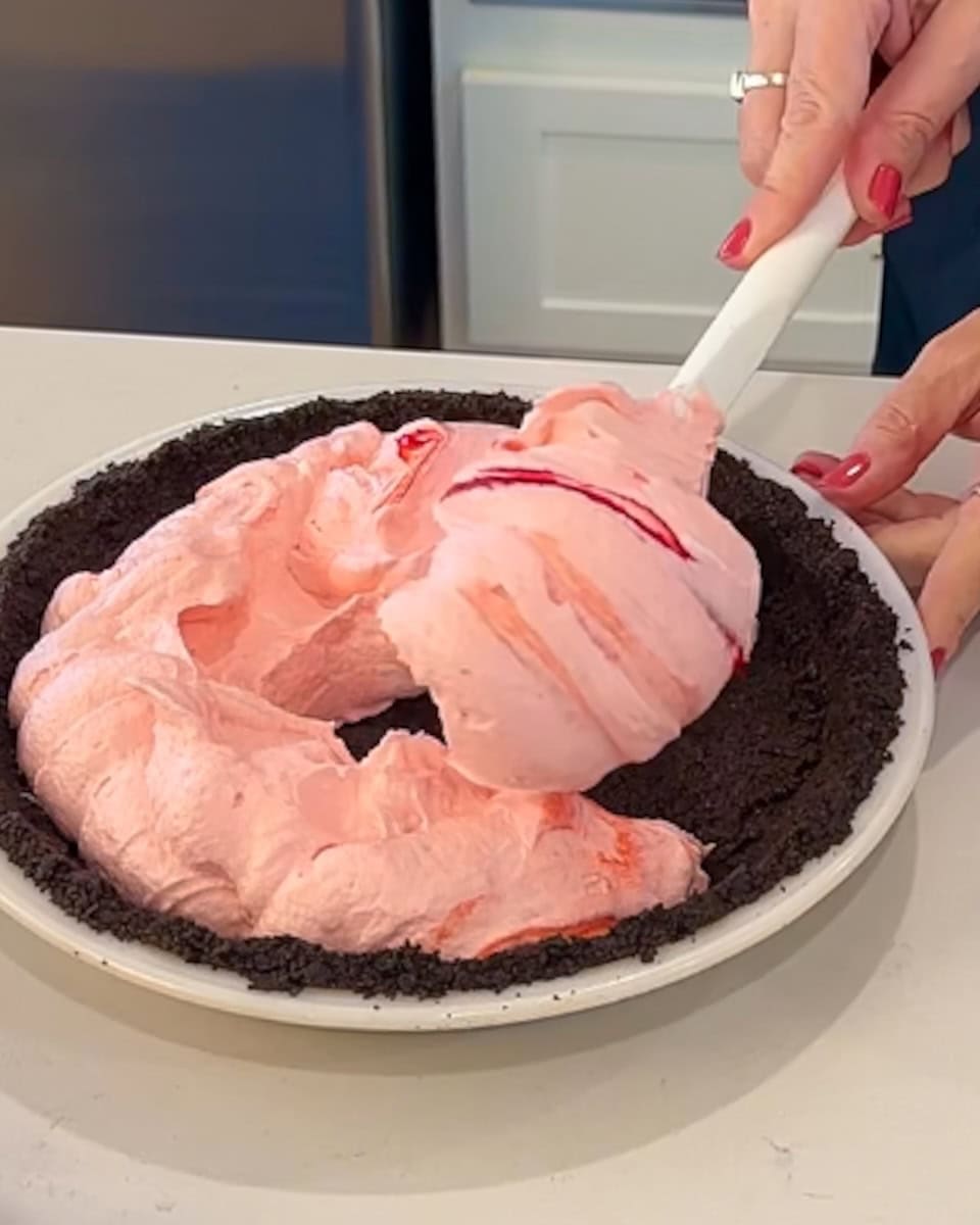 Spooning peppermint filling into a chocolate crust.