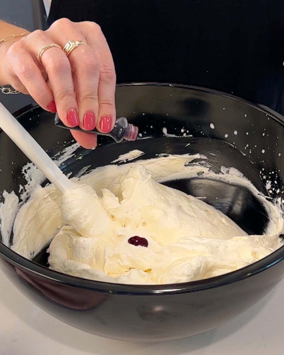 Adding drops of red food coloring to peppermint pie filling.