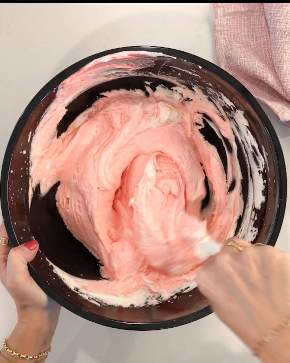 Hand stirring peppermint pie filling to mix in red food coloring.