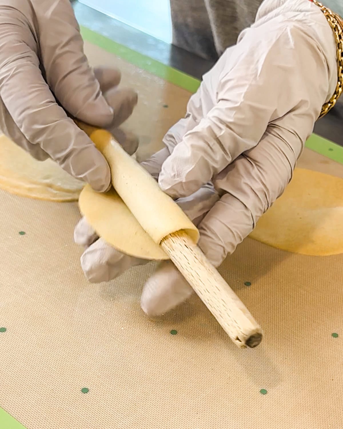 Rolling a warm cookie around a dowel to make a pirouette shape.