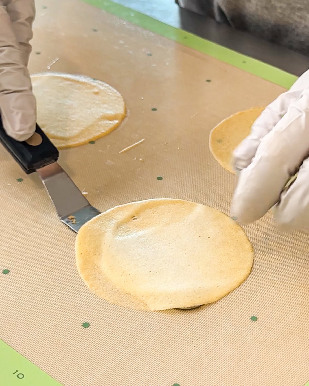 Using a spatula to lift a baked pirouette cookie off the baking tray.
