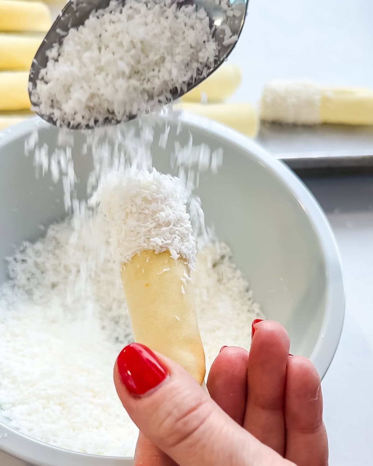 Sprinkling coconut on the tip of a pirouette cookie.